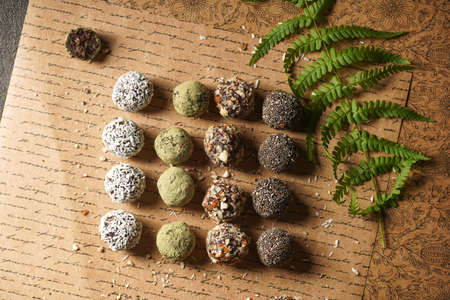 Homemade vegan peanut energy chocolate candy truffles with matcha, chia seeds, almonds and coconut flakes toppingの写真素材