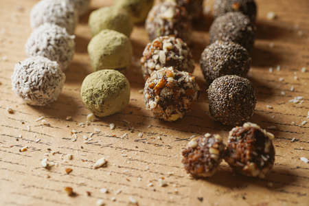 Homemade vegan peanut energy chocolate candy truffles with matcha, chia seeds, almonds and coconut flakes toppingの写真素材