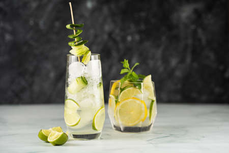 Two different glasses with a drink - cucumber, ice cubes, mint and lime on a dark backgroundの写真素材