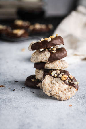 Almond half-chocolate biscuits sprinkled with chopped peanuts and placed on top of each other and milk bottle on light backgroundの写真素材