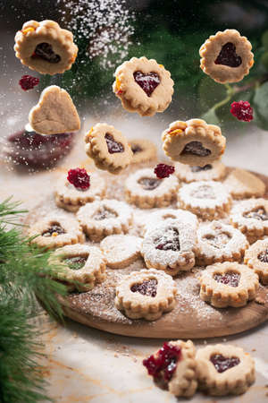 Classic holiday linzer cookies with red jelly cookies with jam hearts flying in the airの写真素材