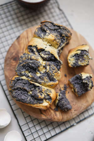 A pastry with poppy on a round wooden board on a black baking rackの写真素材