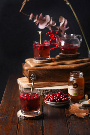 Two glasses with red cranberry tea and honey on a wooden tableの写真素材