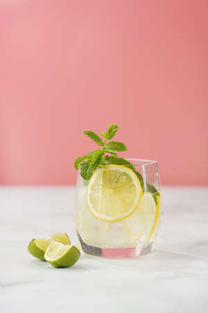 One glass with a drink - cucumber, ice cubes, mint and lime on a pink backgroundの写真素材
