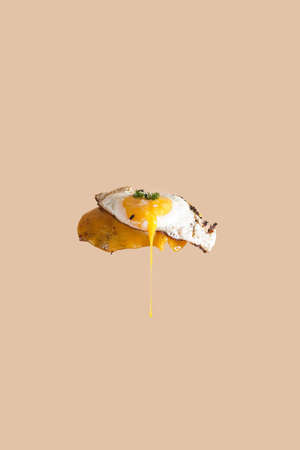 A fried egg on a melting cheddar cheese flying in the air and yolk drippingの写真素材