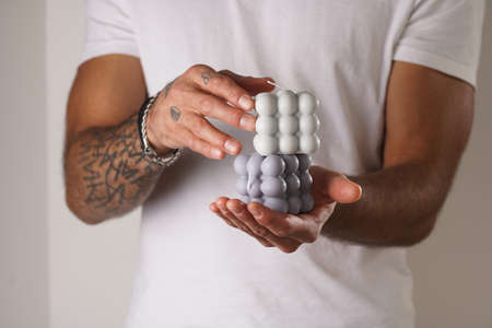 A male hand with tattoos holding a gray bubble candleの写真素材
