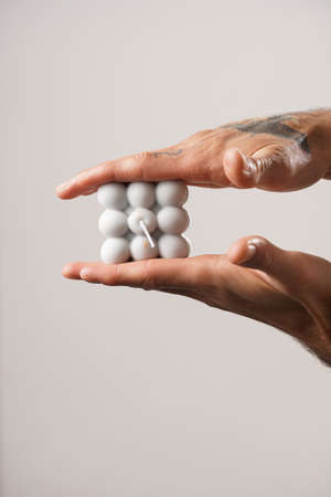 Male hands with tattoos holding a gray bubble candleの写真素材