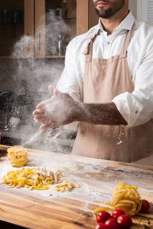 Man chef making italian noodles tagliatelle out of dough in the kitchenの写真素材