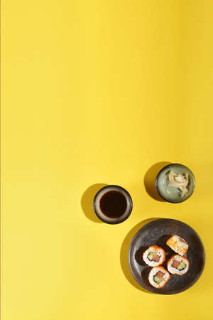 Sushi nigiri with salmon on black plate on yellow background, with soy sauce and ginger, top view, templateの写真素材