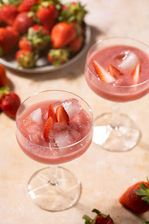 Two glasses with red strawberry dessert with ice cubes and crashed ice and strawberry slices, close upの写真素材