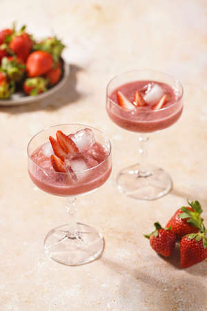 Two glasses with red strawberry dessert with ice cubes and crashed ice and strawberry slicesの写真素材