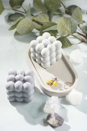 Two gray-blue bubble candles on a concrete tray and white crystals on pastel blue backgroundの写真素材