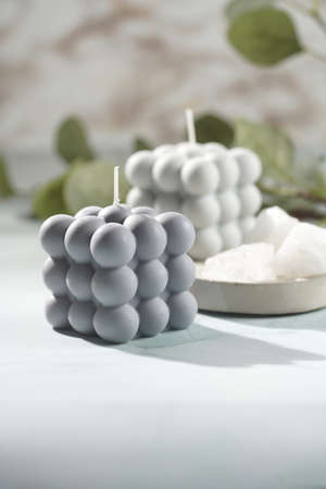 Two gray-blue bubble candles on a concrete tray and white crystals on pastel blue backgroundの写真素材