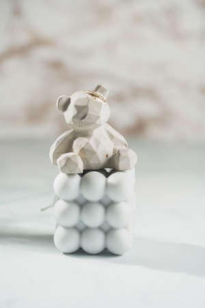 A gray concrete figurine of a teddy bear on a blue bubble candle on pastel blue backgroundの写真素材