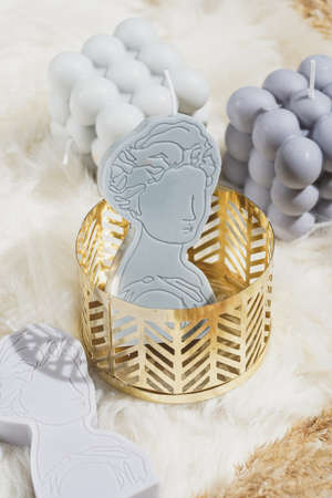 A gray candle shaped as greek goddess in a golden moldの写真素材
