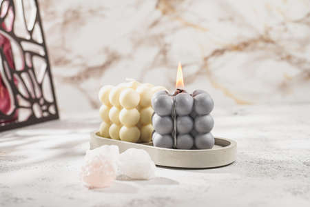 Two gray-blue and white bubble candles on a concrete tray on pastel background, a close upの写真素材