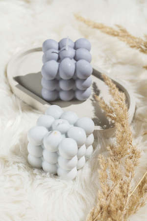 Two gray-blue and white bubble candles on a concrete tray on pastel background, a close upの写真素材