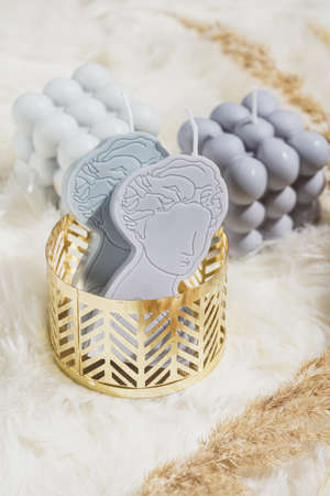 Two gray and blue candles shaped as greek goddess in a golden moldの写真素材