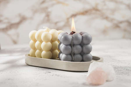 Two gray-blue and white bubble candles on a concrete tray on pastel background, a close upの写真素材