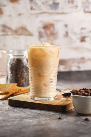 A glass with ice cubes and milk coffee on a wooden boardの写真素材