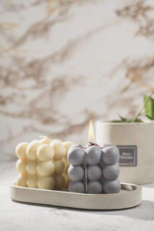 Two gray-blue and white bubble candles on a concrete tray on pastel background, a close upの写真素材