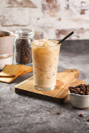 A glass with ice cubes and milk coffee on a wooden boardの写真素材