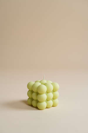 A pastel green bubble candle on an beige colored seamless backgroundの写真素材