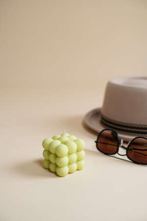 A pastel green bubble candle on an beige colored seamless background, and sunglasses and a hatの写真素材