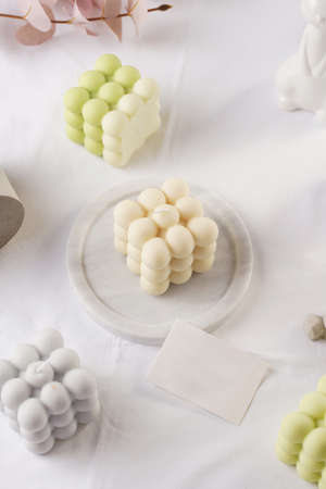 Several bubble candles, gray, patel green and beige on white table clothの写真素材