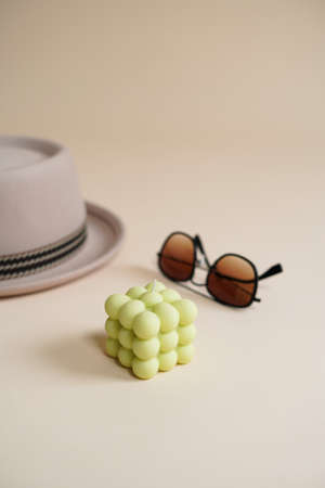 A pastel green bubble candle on an beige colored seamless background, and sunglasses and a hatの写真素材