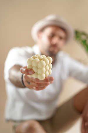 A male hand holding an off-white bubble candleの写真素材