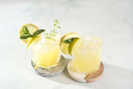 Two ice lemonade drinks in irregular glass with lime pieces and mintの写真素材