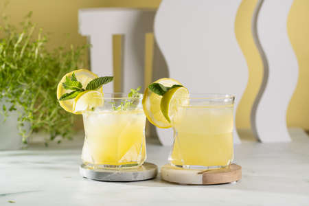 Two ice lemonade drinks in irregular glass with lime pieces and mintの写真素材