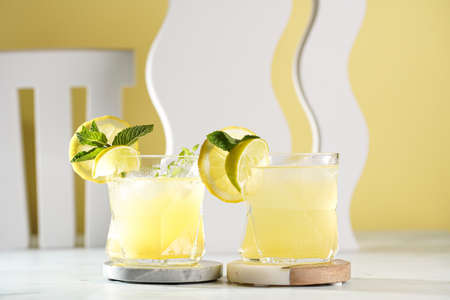 Two ice lemonade drinks in irregular glass with lime pieces and mintの写真素材