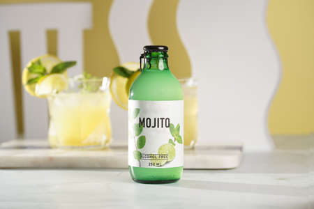 A green bottle with mojito drink and two glasses with lemonade in the backgroundの写真素材