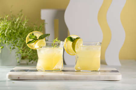 Two ice lemonade drinks in irregular glass with lime pieces and mintの写真素材