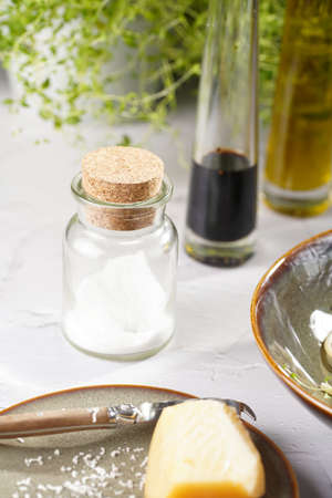 Italian salad dressing ingredients: olive oil, balsamic vinegar, sea salt, thyme and parmesan on white concrete surfaceの写真素材