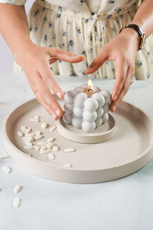 Female hands putting a gray bubble candle on several concrete trays with soy wax piecesの写真素材