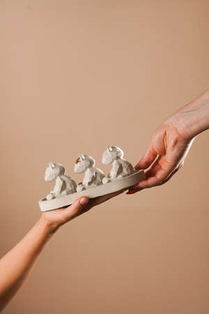 two female hands holding a concrete tray with concrete figurines - teddy-bears facing left