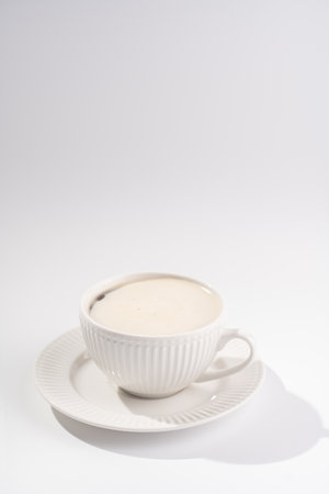 A white porcelain cup with coffee drink cappuccino on a white saucer plate on a white surfaceの写真素材