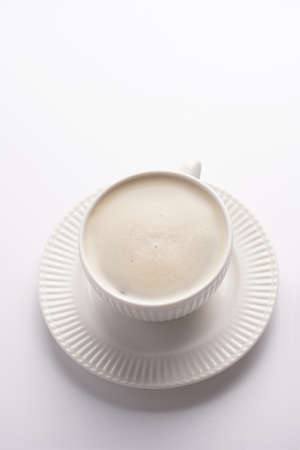 A white porcelain cup with coffee drink cappuccino on a white saucer plate on a white surfaceの写真素材