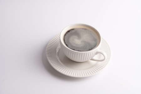 A white porcelain cup with coffee drink cappuccino on a white saucer plate on a white surfaceの写真素材