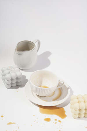 An empty cup with coffee drink on a white saucer plate on a white surface surrounded by bubble candlesの写真素材