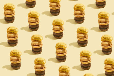 Three creamy and chocolate macaron pastry stacked on top of each other - hard light pattern on beige colored surfaceの写真素材