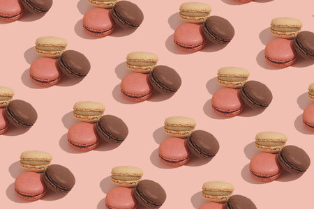 Hard light pattern of a creamy, pink and chocolate macaron pastry on pink backgroundの写真素材