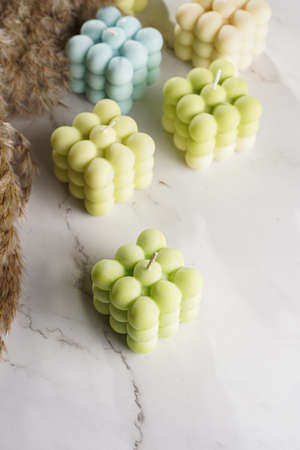 Green, blue and white square bubble candles on a marble surface and pampas grassの写真素材