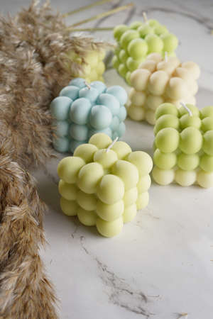 Green, blue and white square bubble candles on a marble surface and pampas grassの写真素材