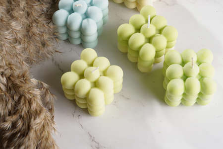 Green, blue and white square bubble candles on a marble surface and pampas grassの写真素材