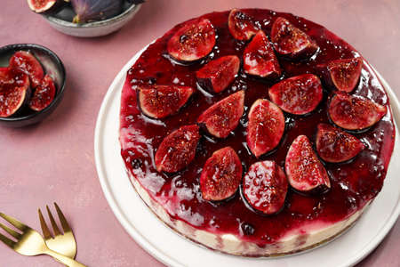 A red cake on a white plate on a burgundy surface: no bake cheesecake with dark red jelly and fig slicesの写真素材