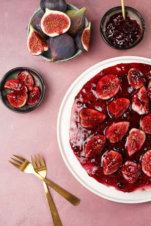 A half of red cake on a white plate on a burgundy surface: no bake cheesecake with dark red jelly and fig slices, top viewの写真素材